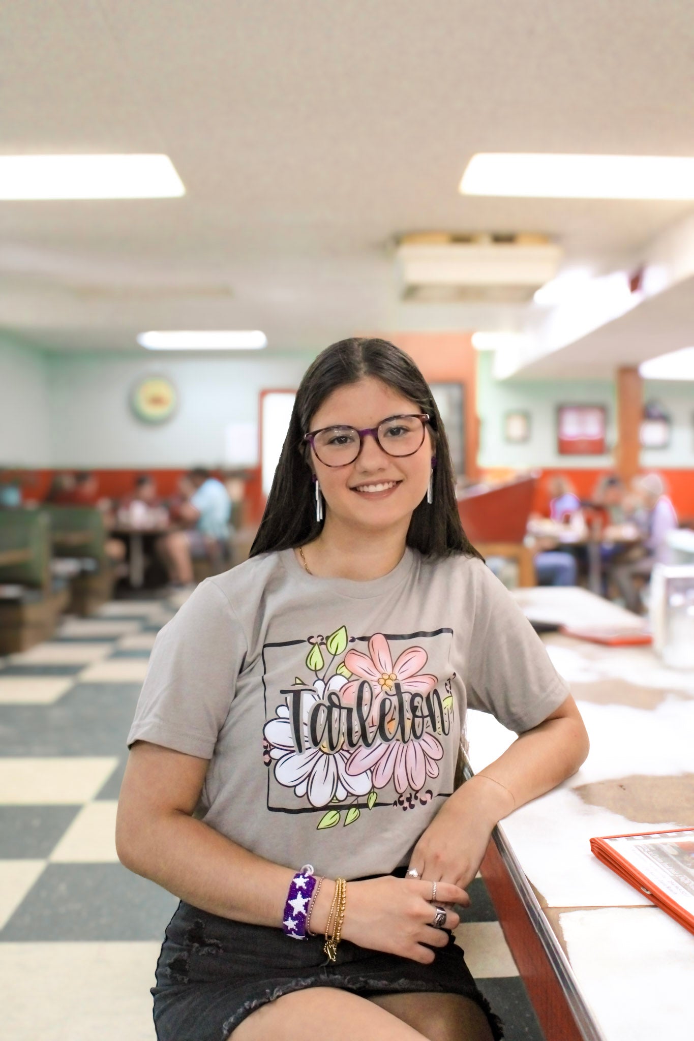 Model wearing a Licensed and Approved Tarleton State University Bella Canvas boho floral graphic t-shirt featuring a hand-lettered Tarleton design surrounded by flowers.